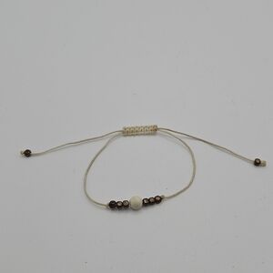 cream colored fabric slider bracelet with brass colored beads